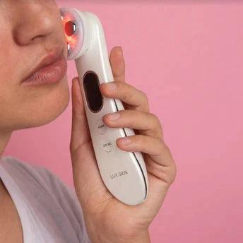 Woman using LUX SKIN® LED Rejuvenation Wand for light therapy on her face, promoting healthy skin.