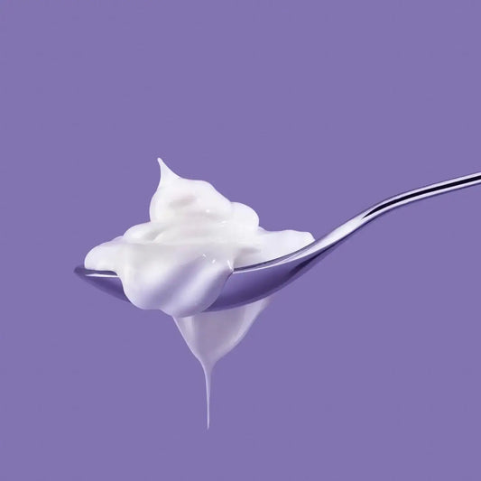 Spoonful of Philip Kingsley Elasticizer Therapies Bluebell Woods cream on purple background.