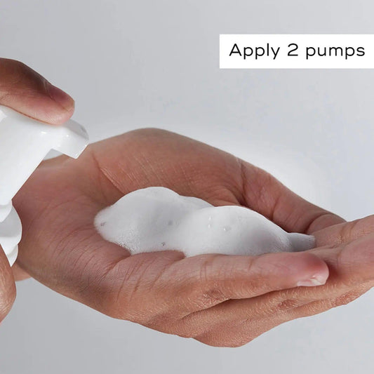 Hand dispensing 2 pumps of Medik8 Micellar Mousse for skincare routine.