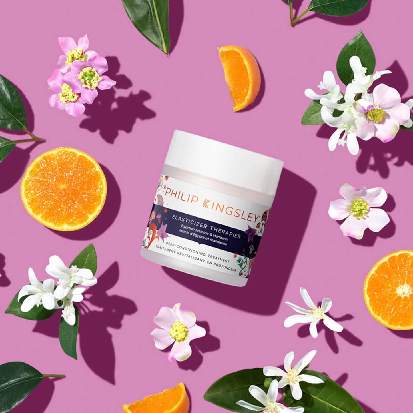 Philip Kingsley Elasticizer Therapies Egyptian Jasmine & Mandarin 150ml on a vibrant pink background with citrus and floral accents.