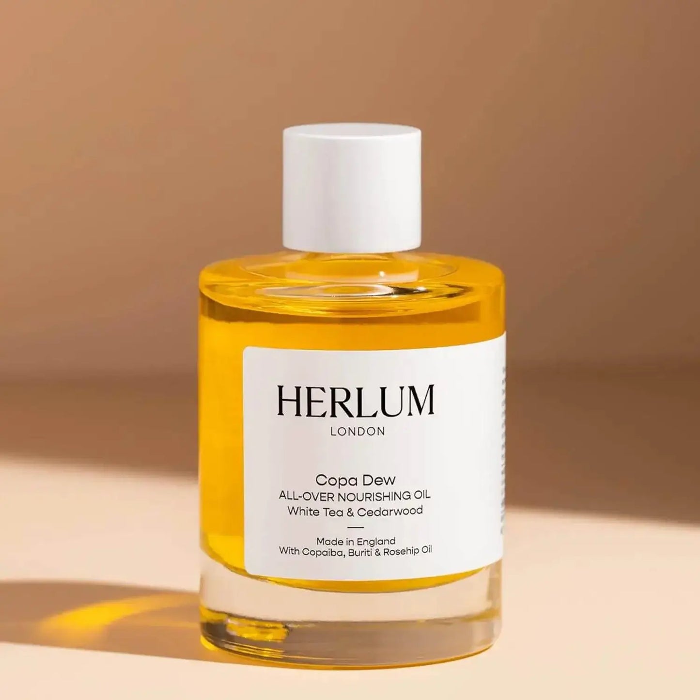 Herlum Copa Dew Oil 50ml bottle showcasing nourishing oil with white tea and cedarwood for radiant skin. Made in England.