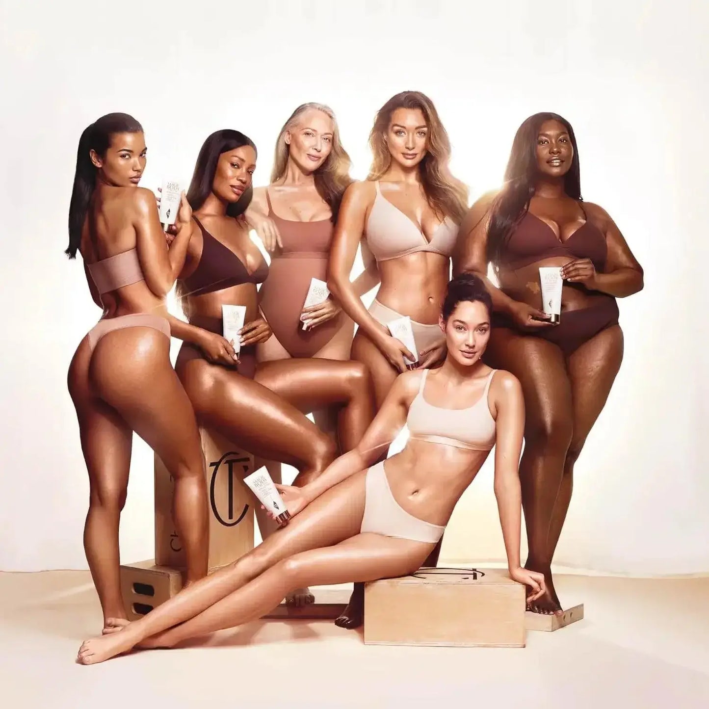 Group of diverse women in swimwear showcasing Charlotte Tilbury's Magic Body Cream 50ml with radiant skin.