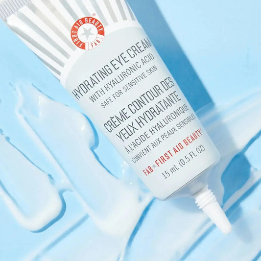 First Aid Beauty Hydrating Eye Cream tube with hyaluronic acid on a blue background, ideal for hydrating and soothing dry eyes.