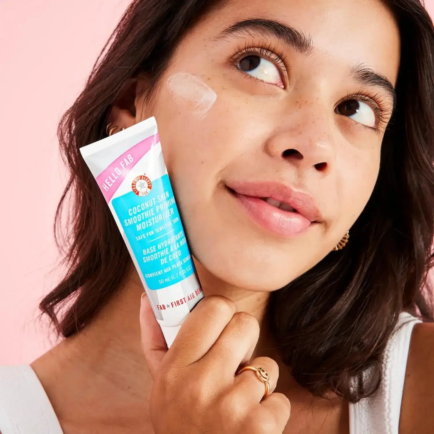 Model showcasing First Aid Beauty Coconut Skin Smoothie Priming Moisturiser 50ml for hydration and makeup longevity.