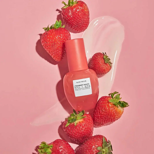 GLOW RECIPE Strawberry Smooth BHA+AHA Salicylic Serum surrounded by fresh strawberries on a pink background.