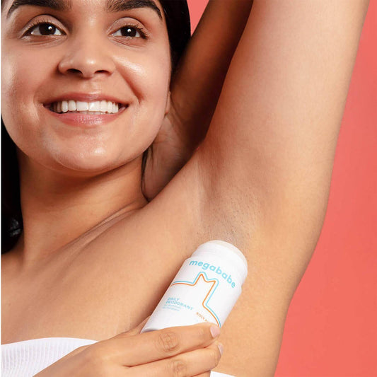 Woman applying Megababe Rosy Pits Daily Deodorant under her arm, showcasing natural odor protection.