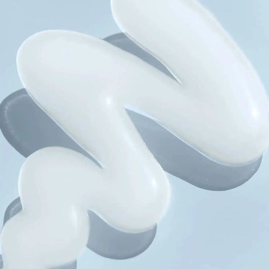 White hydrating serum texture on a reflective surface, showcasing its smooth and creamy consistency.