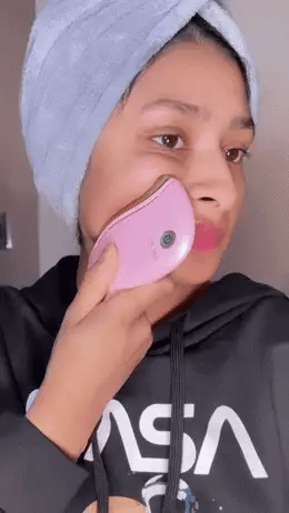 User demonstrating the LUX SKIN® Face Sculpting Tool on their cheek, showcasing its sleek design.