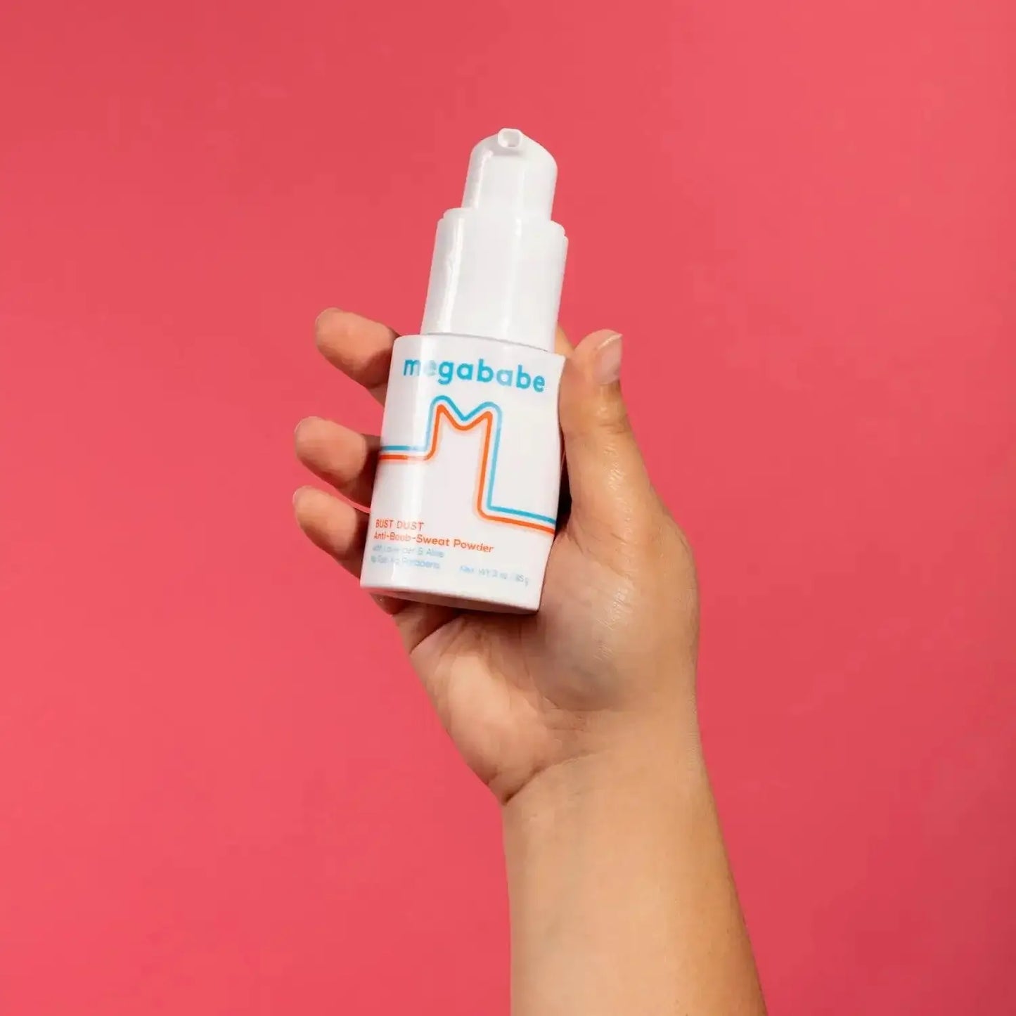 Hand holding MEGABABE Body Dust Mini Top-to-Toe Powder against a pink background.