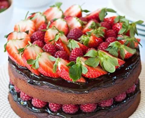 Decadent chocolate cake adorned with fresh strawberries and raspberries, perfect for festive occasions.