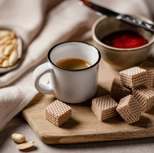 Loacker Peanut Butter Wafer Cookies served with coffee and jam on a wooden board, featuring a cozy snack arrangement.
