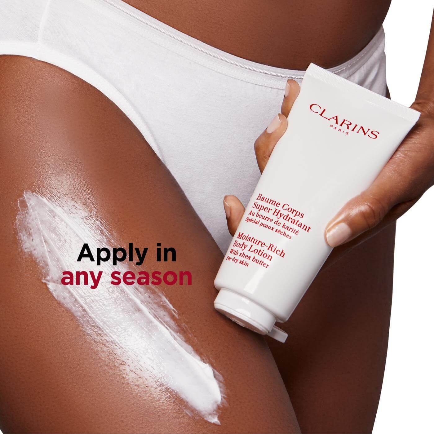 Clarins Moisture Rich Body Lotion being applied to skin, showcasing its hydrating properties with Shea Butter.