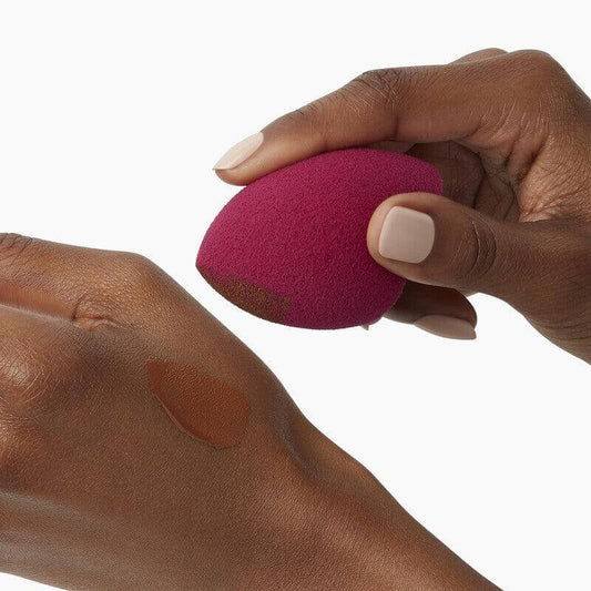 e.l.f Total Face Sponge Duo: Latex-free sponge in hand with foundation swatch on skin, ideal for blending and concealing.