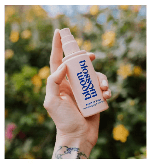 Bloom and Blossom Spritzy Toes Revitalising Leg and Foot Spray in hand, ideal for soothing tired legs and feet.