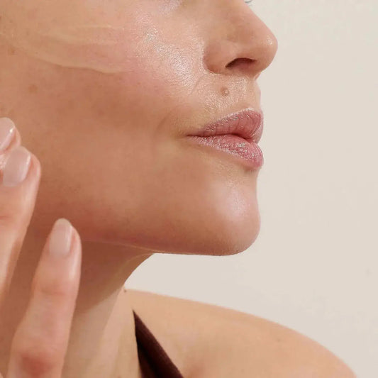 Close-up of a woman applying Balance Me Rose Otto Face Oil to her skin, highlighting its moisturizing properties.