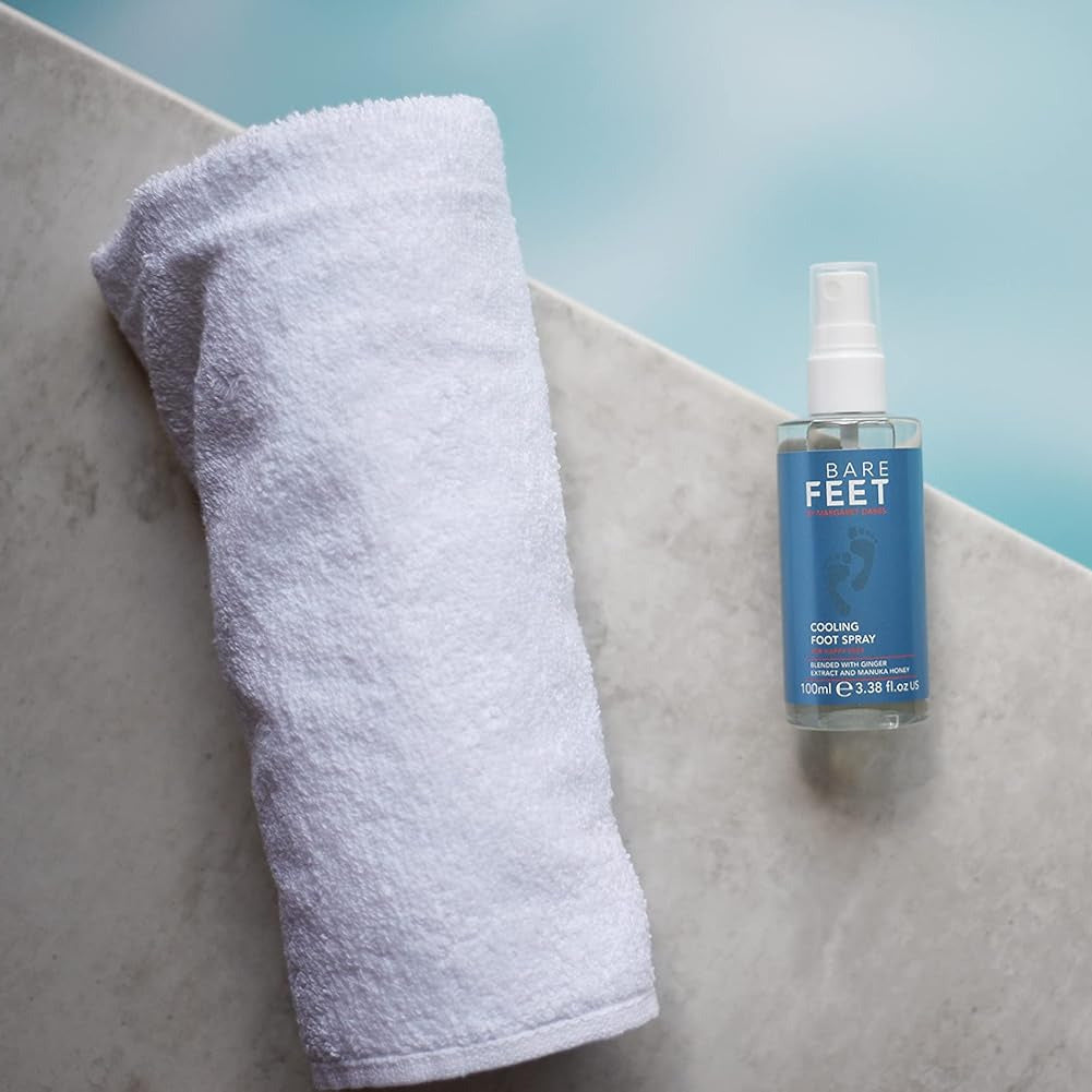 Bottle of 'Bare Feet' spray next to a white towel on a light blue background