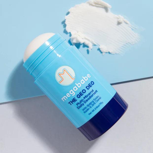 Megababe The Geo Deo Multi-Mineral Daily Deodorant stick on a blue background, featuring a creamy texture.