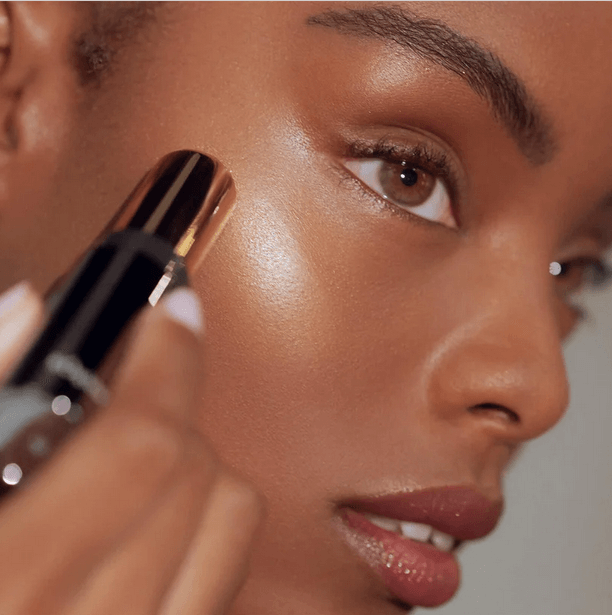 Close-up of a woman applying RÓEN RÓGLOW Skin Stick for a radiant, luminous glow.