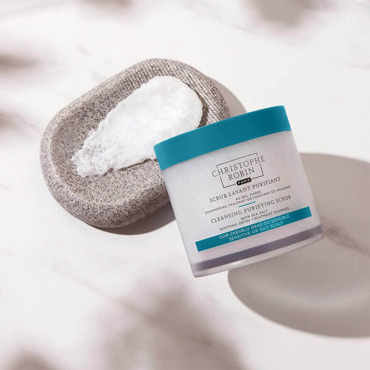 CHRISTOPHE ROBIN Cleansing Purifying Scrub with Sea Salt on a stone dish, perfect for exfoliating scalp and removing buildup.