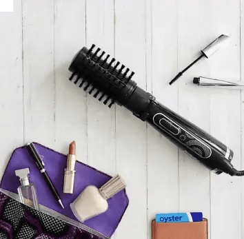 BaByliss Big Hair 2885U Spinning Brush next to beauty products on a white wooden surface.
