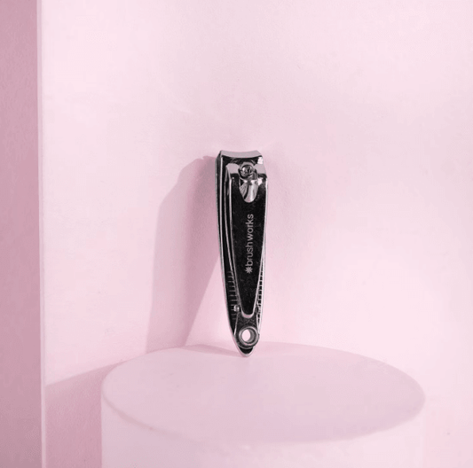 Brushworks Nail Clipper on a pink background, showcasing its stainless steel design for easy nail care at home.
