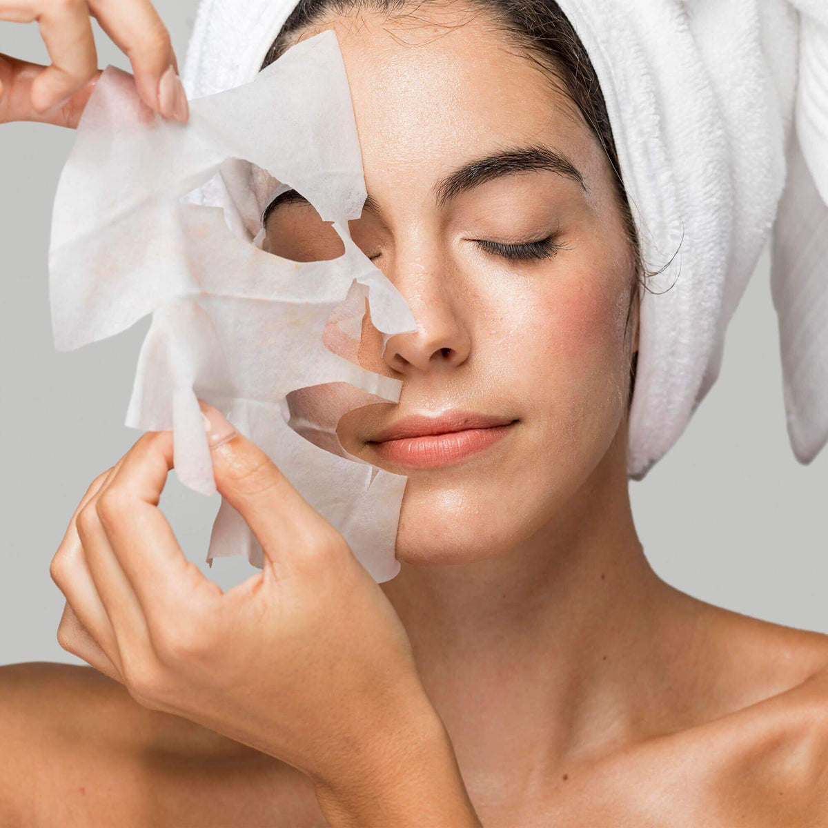 A woman applying a BeautyPro SQUALANE Nourishing Facial Sheet Mask, showcasing rejuvenating skincare routine.
