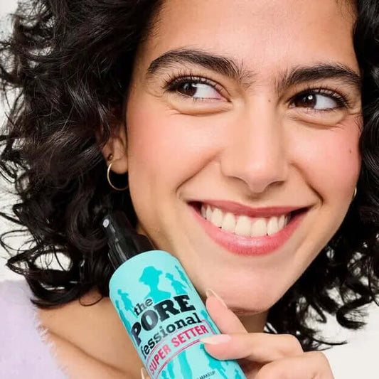 Smiling woman holding Benefit POREfessional Super Setter 15ml, showcasing its pore-blurring and makeup-setting features.