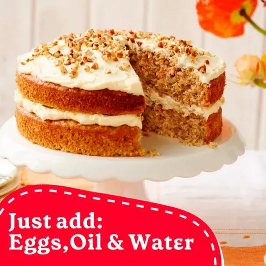 Sliced Betty Crocker Carrot Cake with cream cheese icing on a decorative stand, featuring walnuts on top.