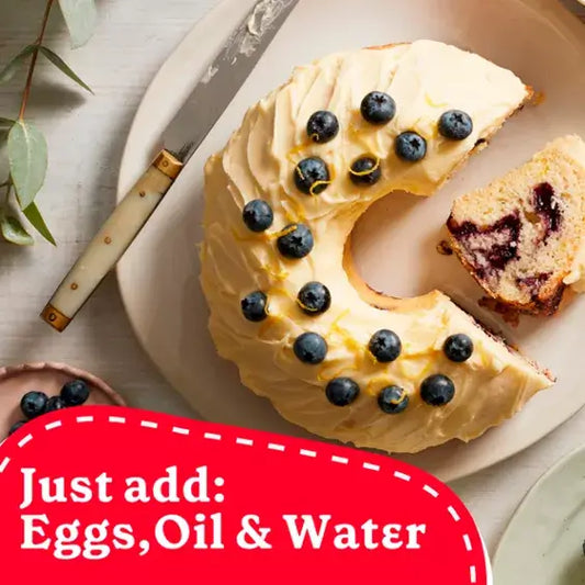 Sliced lemon cake topped with blueberries on a plate, with knife and text overlay: Just add: Eggs, Oil & Water.