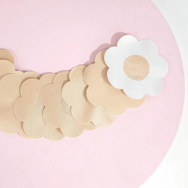 Brushworks Satin Petal Nipple Covers displayed on a pink background, featuring a smooth, discreet flower-shaped design.