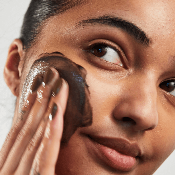 Woman using Carbon Theory Charcoal & Tea Tree Oil Facial Cleansing Wash on her face for clear, refreshed skin.