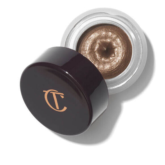 Charlotte Tilbury Makeup product with a dark brown lid and metallic brown cream inside, on a white background.
