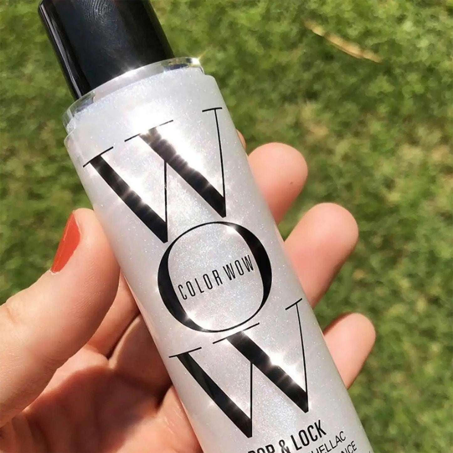 COLOR Wow Pop & Lock High Gloss Finish spray in hand, showcasing its travel-size design and shimmering formula.