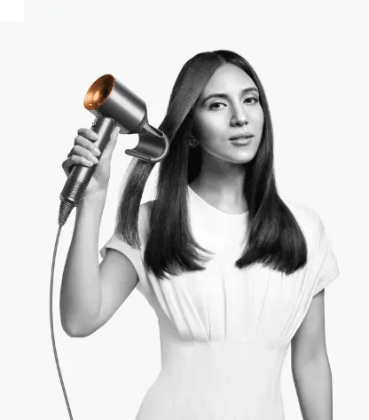 Dyson Supersonic Hair Dryer in Nickel/Copper held by a woman with long hair, showcasing fast drying and styling features.