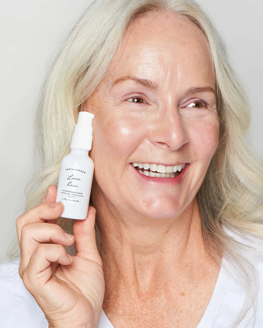 Woman holding an Earth Harbor skincare product with a plain background