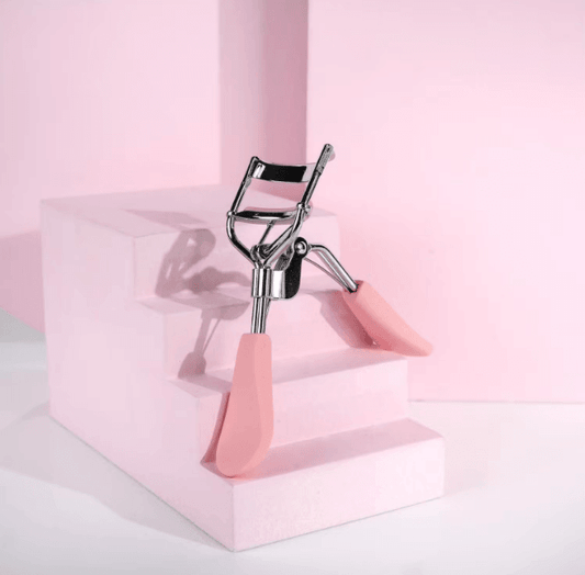 Brushworks Lash Curler on pink steps, featuring ergonomic handles and rounded silicone pads for effortless lash curling.