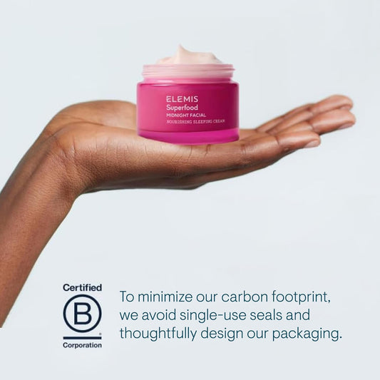 Hand holding a pink Elemis skincare product with a gray background