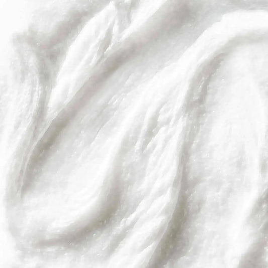 First Aid Beauty Face Cleanser texture close-up, showcasing a creamy white formula for gentle cleansing.