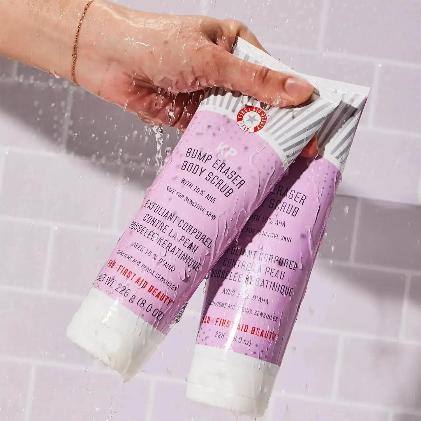 First Aid Beauty KP Bump Eraser Body Scrub in hand, showcasing 10% AHA for smooth skin, 226g packaging.