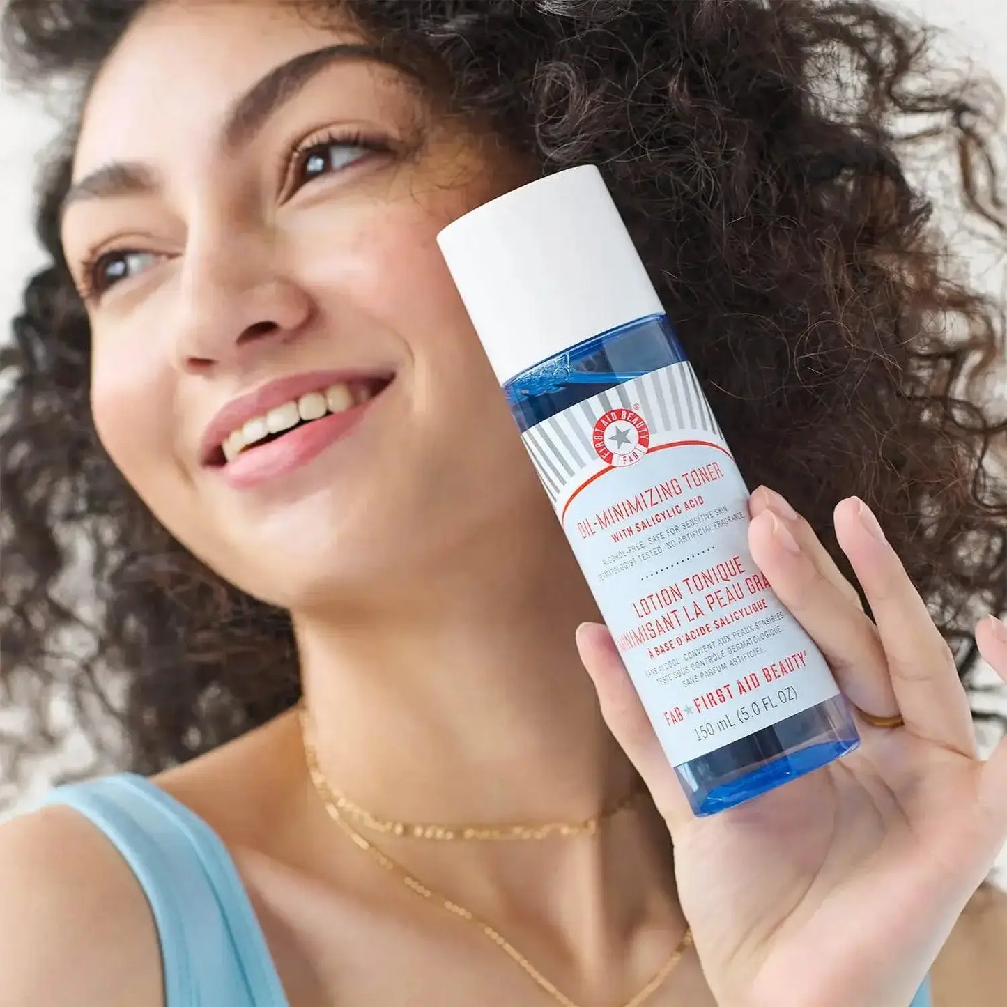 First Aid Beauty Oil-Minimizing Toner with Salicylic Acid in a woman's hand, promoting a clear complexion.