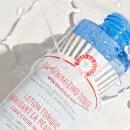 First Aid Beauty Oil-Minimizing Toner with Salicylic Acid 150ml on a white surface with water droplets.