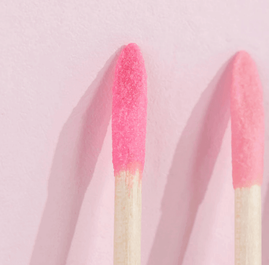 Close-up of pink Brushworks crystal cuticle sticks on a pastel background for healthy nail care.