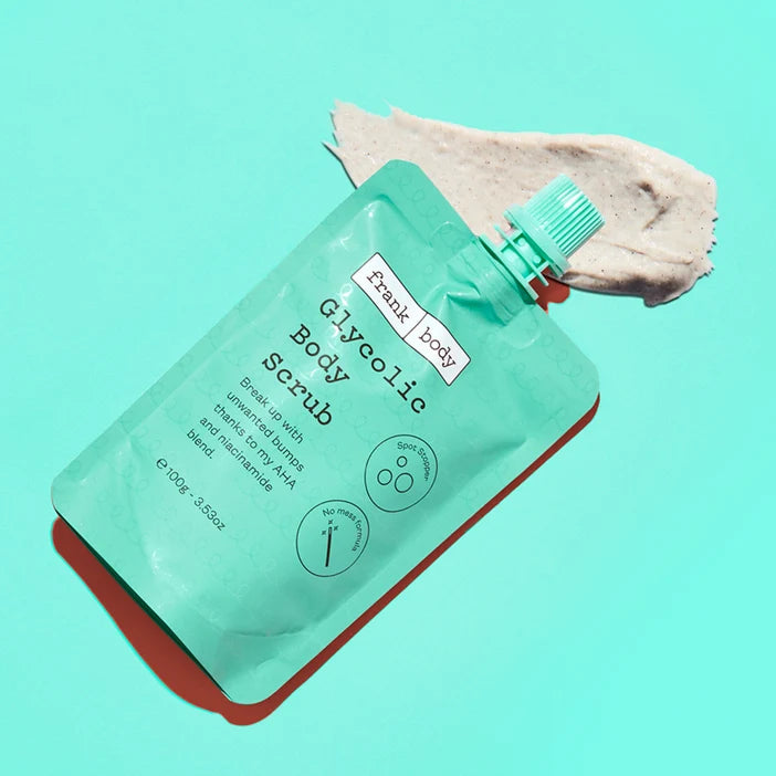 Green body scrub packaging with a swatch of scrub on a teal background