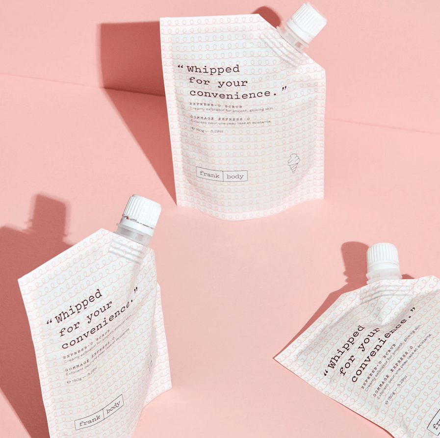 Three white pump Frank Body bottles with text on a pink background