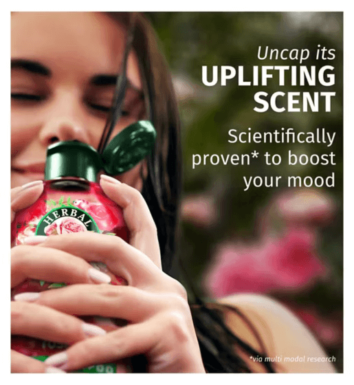 Woman enjoying Herbal Essences shampoo, showcasing mood-boosting benefits, with rose scent in a floral background.