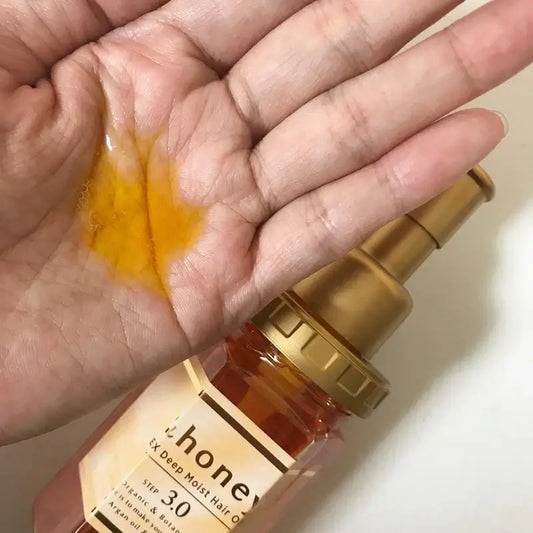 Hand holding a bottle of honey with a close-up of honey on the palm.