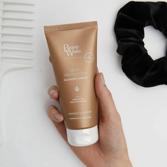 Beauty Works Blowdry Crème 100ml tube held in hand with heat protection features for healthy hair styling.