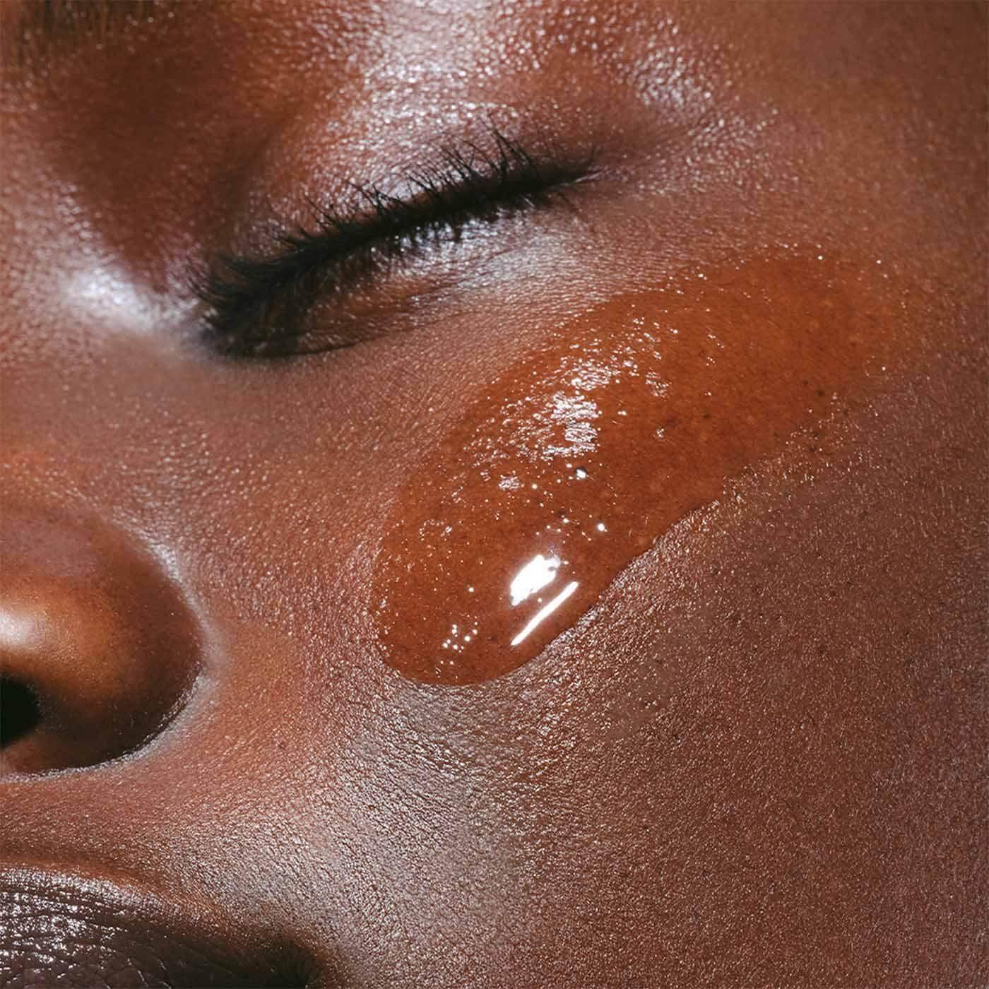 Close-up of a woman's cheek applying Clarins Hydrating Toning Lotion for glowing, moisturized skin.