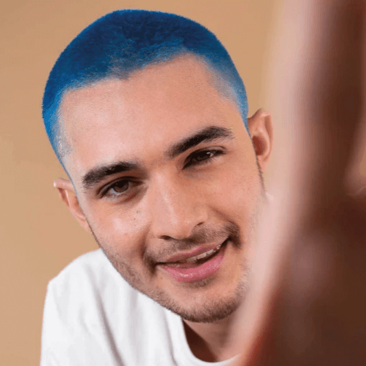 Man with vibrant blue hair glaze showcasing the bold color transformation on a neutral background.