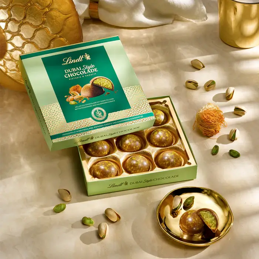 Lindt Dubai Style Chocolate Pralines 90g in elegant packaging, surrounded by nuts and decorative elements.